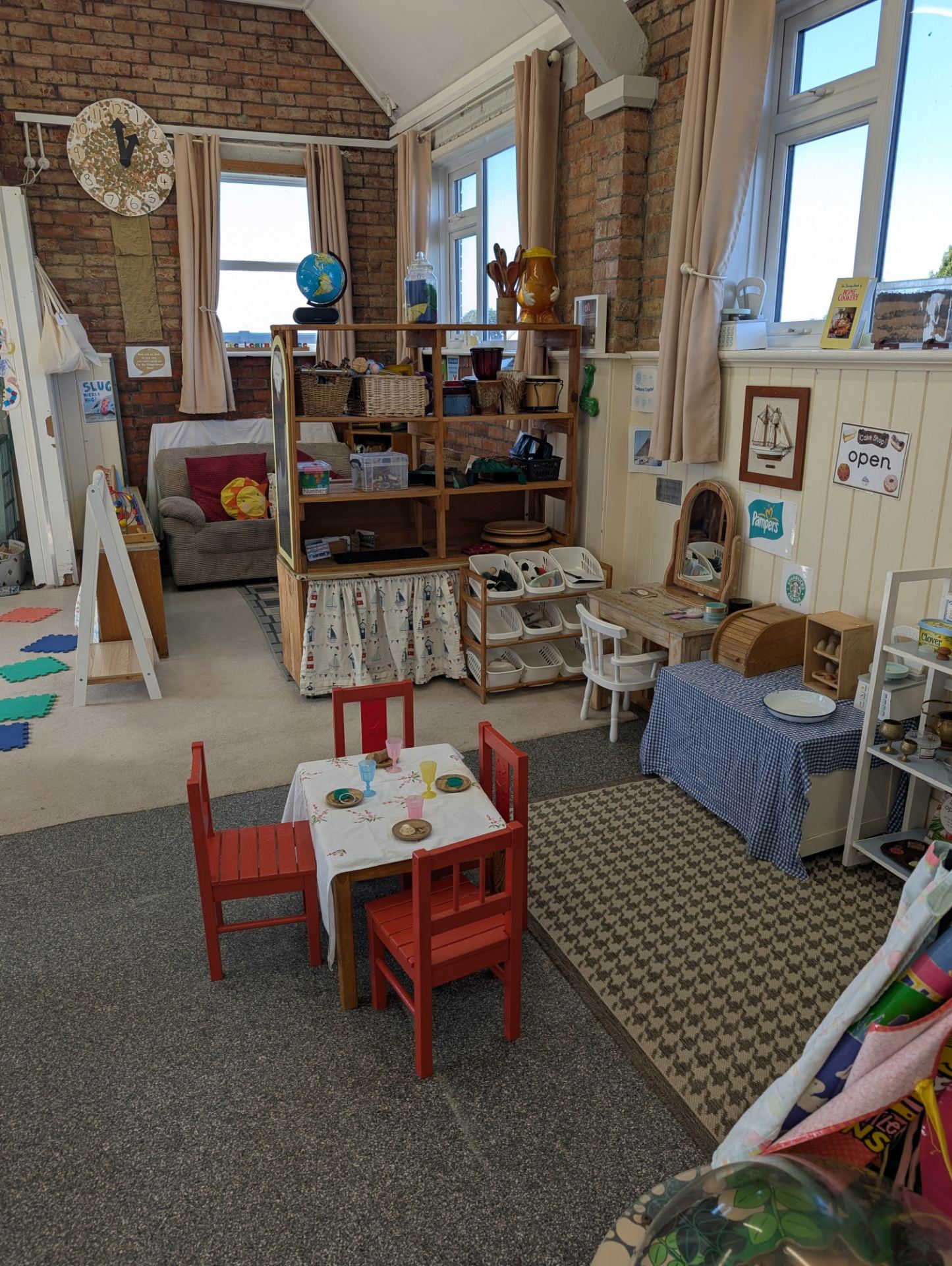 A bright, well-organised early-years classroom in a converted brick building with high ceilings and large windows.