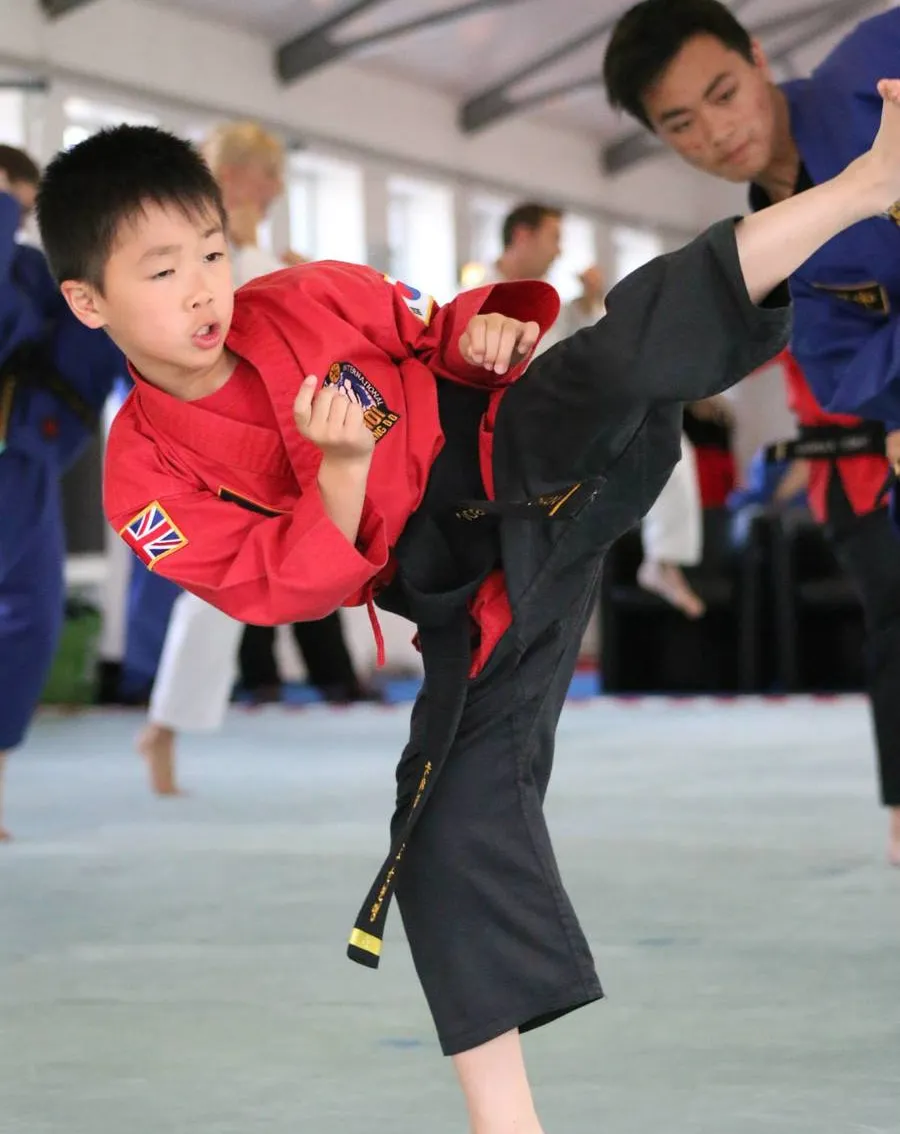 Child performing a high kick in martial arts class